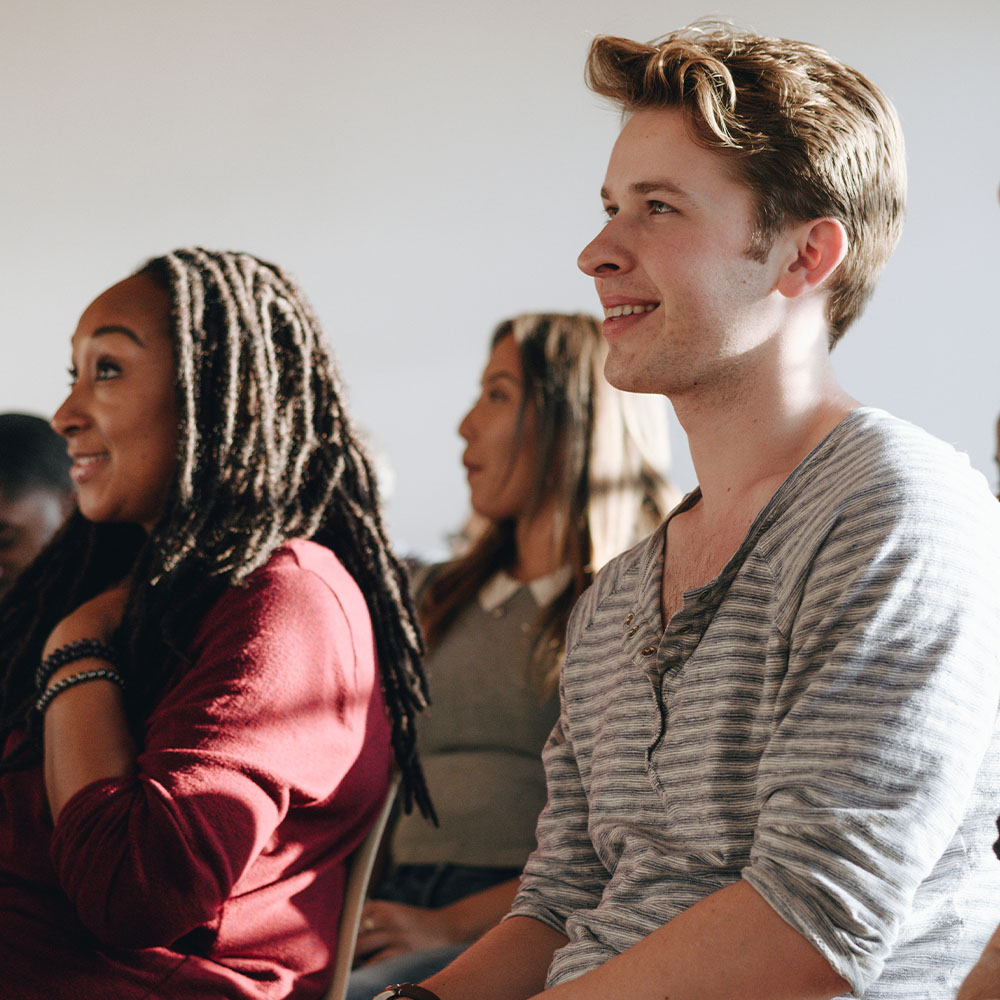 Diverse group of adult audience members with surprised expressions, focusing on two specific audience members