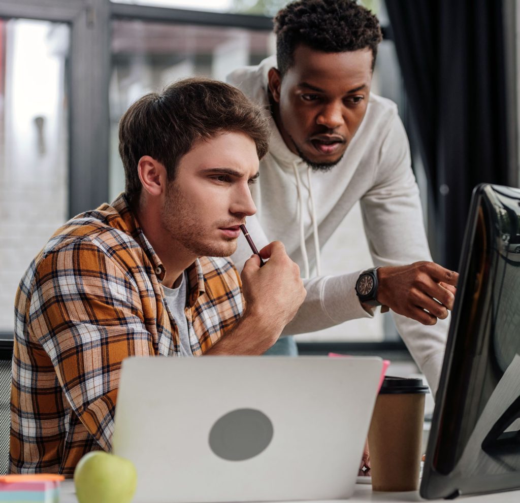 programmer pointing at computer monitor near colleague