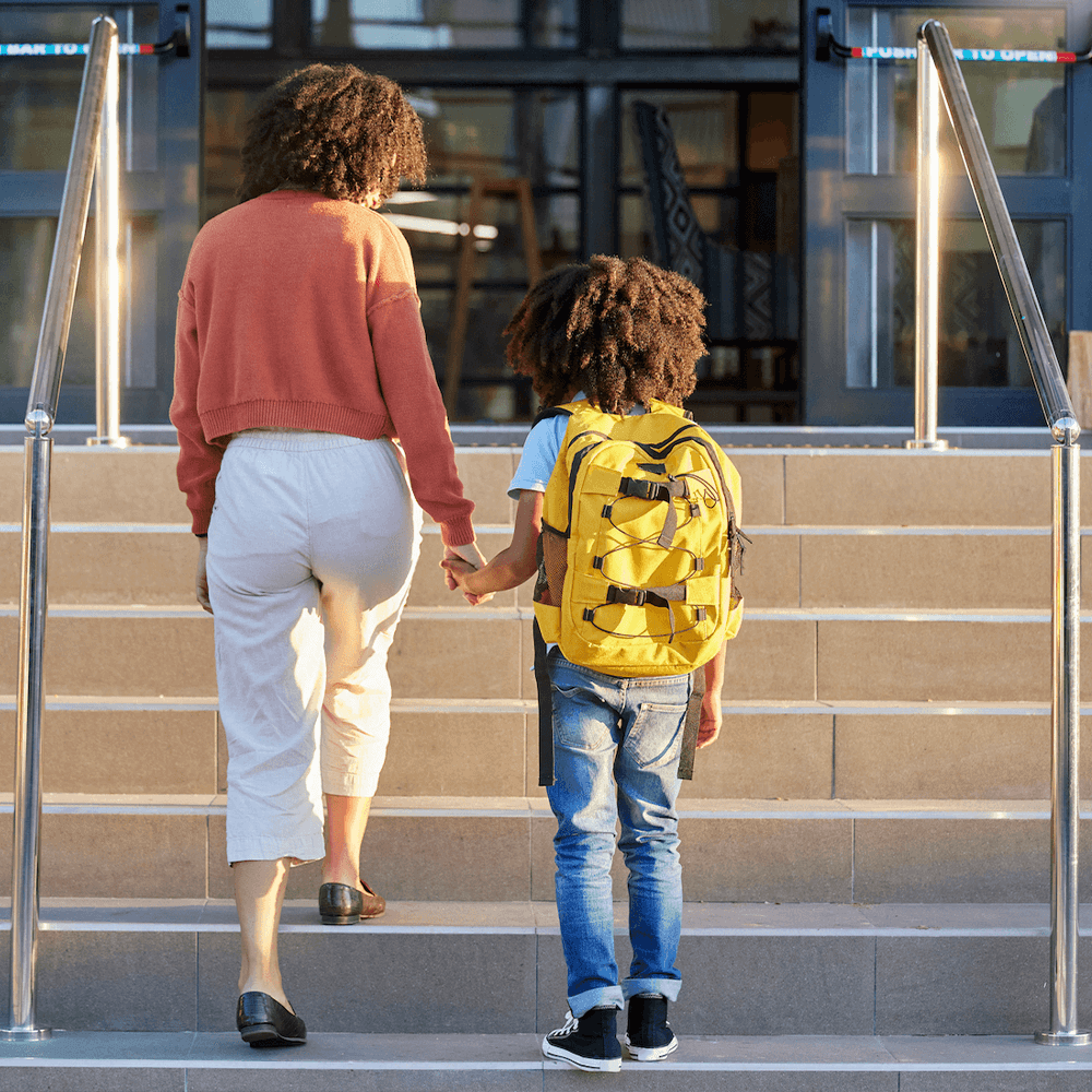 Parent and child walking into entrance of school