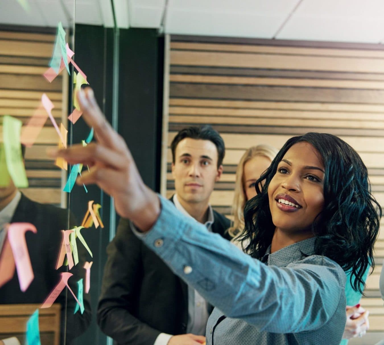 Business woman reaches for a sticky note on wall