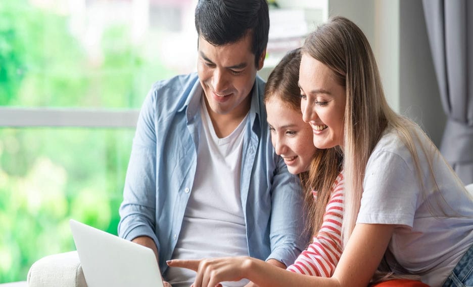 Family of three looking at a laptop