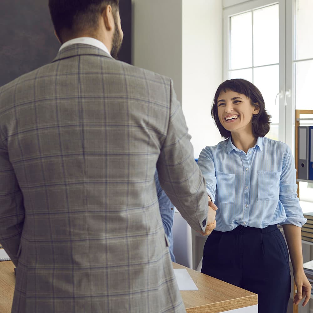 Businessman and woman happily shaking hands in an office