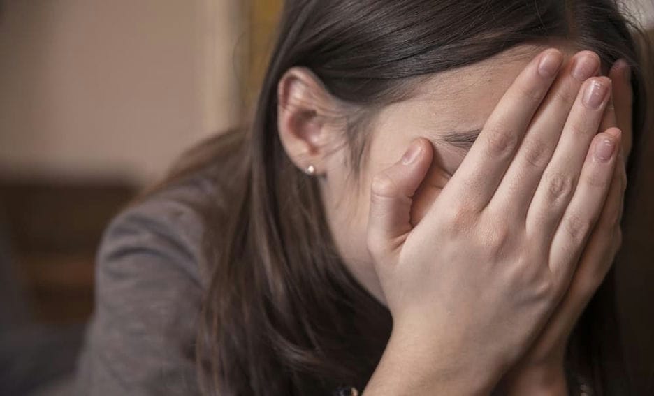 A distressed student with their head in their hands.