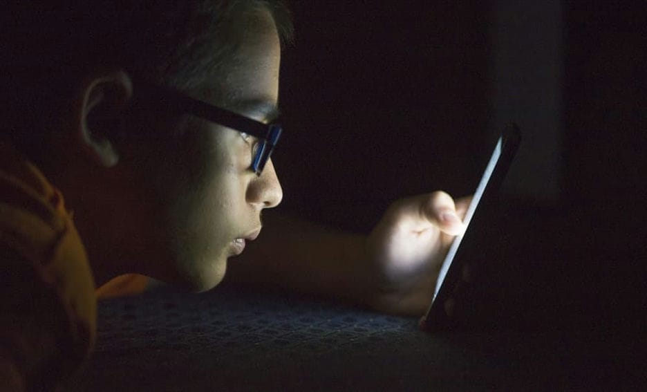 Student on his phone in the dark