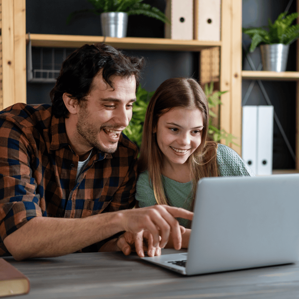 Smiling father and daughter looking at laptop