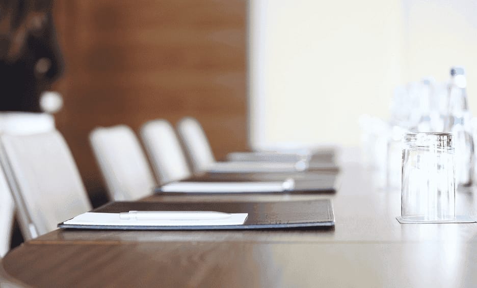 Empty conference room with desks, notepads, and water bottles