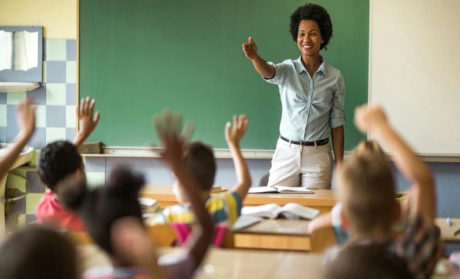 Teacher pointing to students whose hands are raised