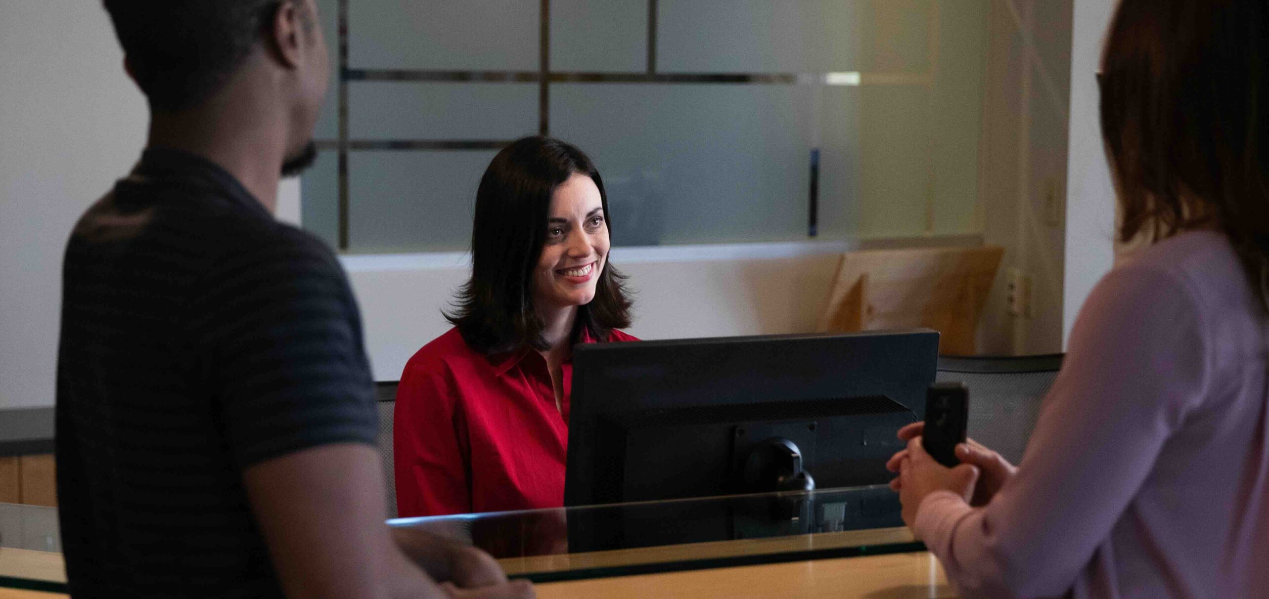 Friendly receptionist greeting guests in office lobby